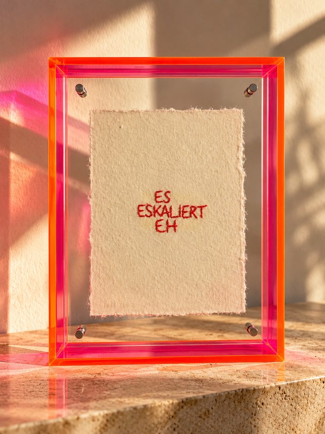 ES ESKALIERT EH – Handstickerei im Neon-Plexiglasrahmen