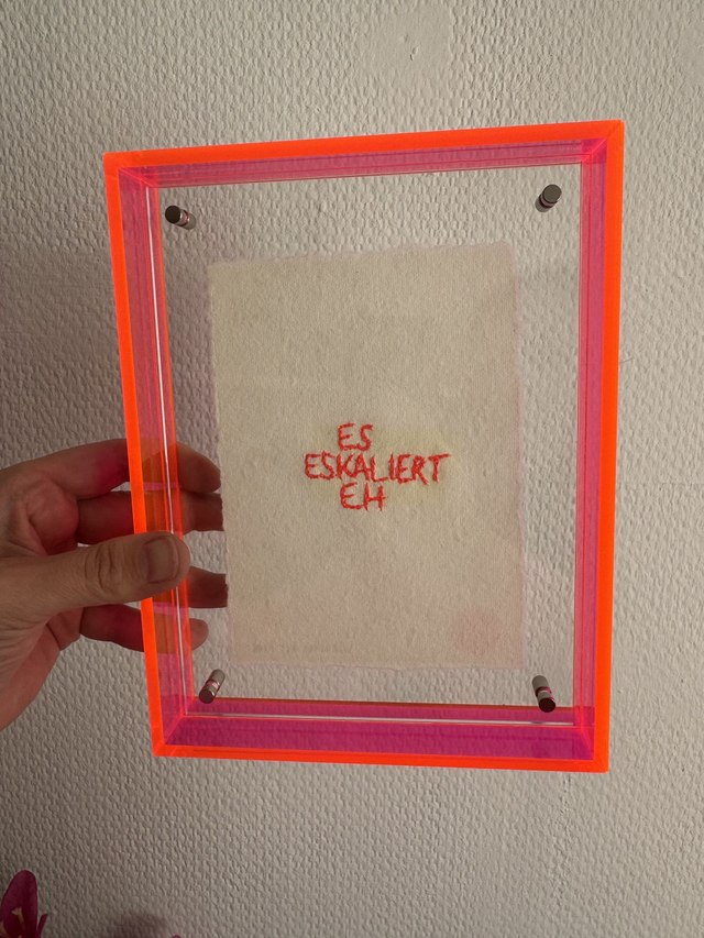 ES ESKALIERT EH – Handstickerei im Neon-Plexiglasrahmen